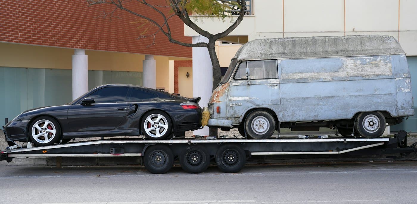 Une remorque porte-voitures chargée d’une voiture de sport et d’un vieil utilitaire